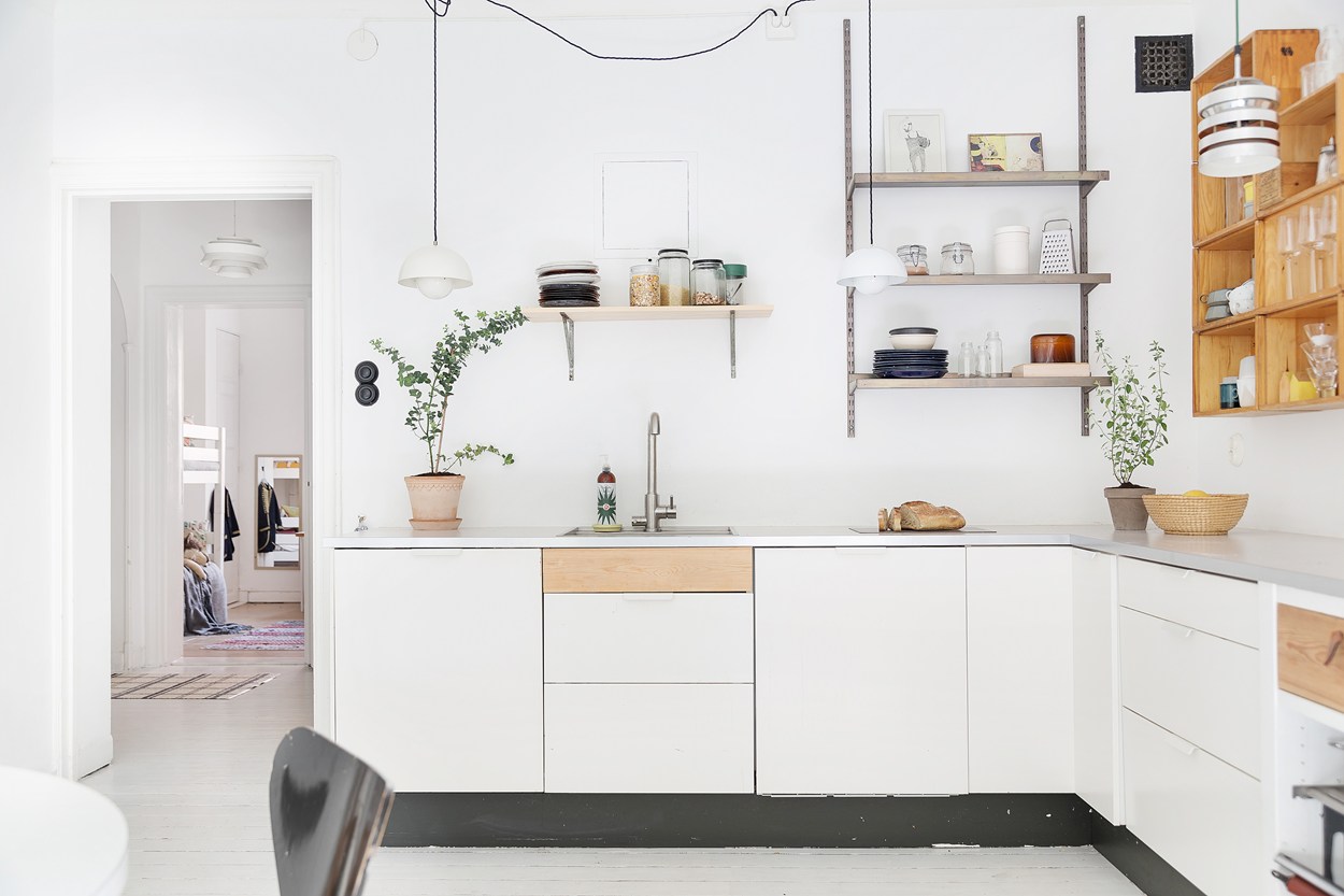 minimalist kitchen inside of a scandinavian farmhouse with white painted floors, midcentury modern lamps