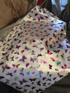 Beautiful, small foil multi-colored butterflies on white satin fabric