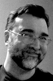 B&W photo of man with short hair, beard, and glasses