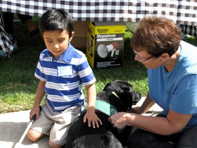 A youngster meets a black Lab Guide Dog puppy at the Blind Babies Foundation beep Easter egg hunt