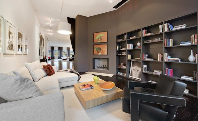 Den in a Soho Condo in New York with white sofas, a low wooden table, gray wall bookcase and fireplace