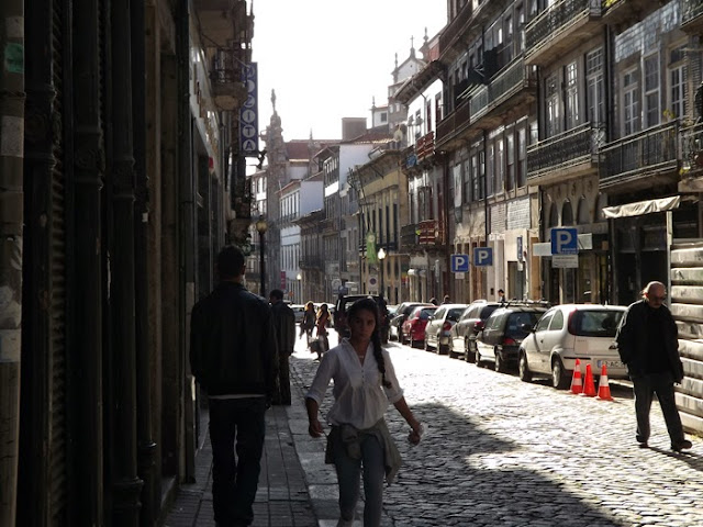 antiga rua das Flores com carros estacionados e pessoas caminhando no passeio