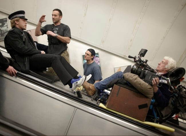 60 Iconic Behind-The-Scenes Pictures Of Actors That Underline The Difference Between Movies And Reality - Javier Bardem slides down an Underground escalator on the set of the 2012 Bond film, Skyfall.