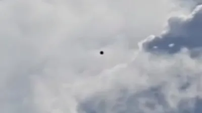 Close up of a black UFO Orb in the clouds.