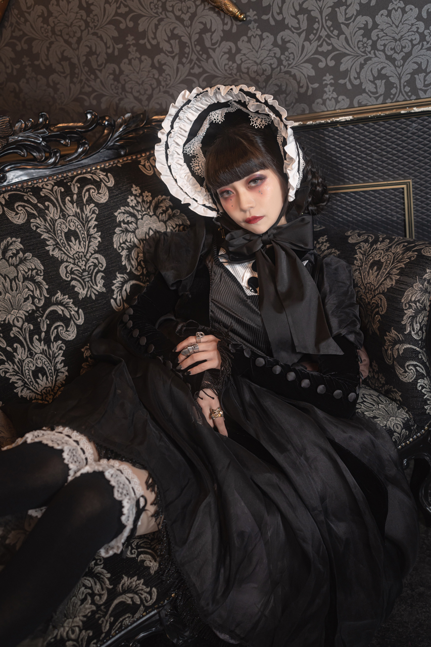 young woman in gothic lolita fasion outfit is posing in a room