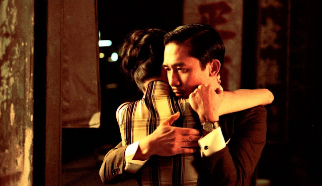 Film Review:  Wong-Kar-Wai is a Hong Kong second wave filmmaker. He wrote screenplay, produced and directed together 'In The Mood For Love' in 2000.Though the introduction of the film starts with some of the common scenes, he creates some extra-ordinary scenes and makes the film extra-ordinary with his skills.  Introduction,naming and accessory discussion:-  Hong Kong Filmmaker Wong-Kar-Wai directed some other films before. As a result of getting successful of those films, he starts to direct his 'In The Mood For Love'. At first, he gave a Chinese name of the film ''the age of blossoms'' or ''the flowery years'' which is derived from a song of a same name by Zhou Xuan from a 1946 film. The English Title of the film derived from the song "In The Mood For Love''. At first, Wong-Kar-Wai kept it secrets but after listening the song from the film he selected the title and gave the name ''In The Mood For Love''. It was one of the great films of 2000s. Besides, it is one of the important and noticeable films in Asia. It is also the second part of his 'Trilogy'. The first part or film is 'Days of Being Wild' (1990) and the last part is ''2046'' released in 2004.  Plot of the film:   Hong Kong-1962:  The event of the film takes place in 1962. There are two main characters. Chow-Mo-Wan and Su Li-zhen. Mr. Chow is married and a reporter of a Newspaper. His office is in Hong Kong. On the other hand, Su Li-zhen is also married. She works at a shipping company as a secretary. Both Mr. Chow and Su Li-zhen simultaneously come to rent their different flats. But they rent their flats alongside. Sometimes, Su comes down from flat to buy food. As both of them stay at the second floor, sometimes when they come down and go on at the stair, they meet and say 'Hi', 'Hello'. Both of them simultaneously come to home from their jobs and they meet for a very short time. Su's husband Mr. Chan is in Japan for business. On the other hand Mr. Chow's wife is also in abroad for business. Both of them are busy with their deeds. So, they can't come to home such that. Meanwhile, there is made a relationship between Mr. Chow and Mrs. Chan (Su). They start their conversation at a hotel about tie and vanity bag. Chow says, 'Your bag is very beautiful and extra ordinary. Where have you bought it? A bag is needed for my wife too.' Su says, 'Her husband has taken it from abroad.' But she adds that Mrs. Chow also uses this kind of a bag. Mr. Chow says 'Yes'. He says her boss has given it to her. On the other hand, Su says, 'your tie is very beautiful and attractive. From where have you bought it? Mr. Chow says, ‘My wife has taken this buying from abroad. This kind of tie is unavailable without abroad.’ But Su knows her husband sometimes wears this kind of tie by borrowing. She tells about this to Mr. Chow. Thus a relationship is made up between them. After few days, they can know that their husband and wife have a different relation, besides business, and Mrs. Chow is also in Japan with Mr. Chan. Who knows how much deep their relationship is! But thinking about these matters, when Mr. Chow and Su fall in love, they are able to know this latter. Chow feels sick. Su cooks for him secretly. Even the owner of the flat of Chow, Mr. Koo also can’t know. On the other hand, the owner of the flat of Mr. Chan, Mrs. Suen and her family can’t know about their relationship and their deeds. The relationship of them becomes deeper. But they admit that their relationship is not like them (Mrs. Chow and Mr. Chan). They won’t vitiate their pure love. Su regularly watches film. On the other hand, Chow writes ‘Martial Arts’ for the paper. But Su like to read this. Once, both of them write discussing it. There is no lack of money of Mr. Chow and Su. But they can only talk with each other sometimes at stair, sometimes at the street. But no other can talk at home. If the owners of those flats are able to know about their relationship, for this, they sometimes talk at stair, sometimes at the street, sometimes going to buy foods. Once, Mr. Chow rents a room at a hotel. Both of them congregate at the hotel room. They talk about their matters, they talk about their wife and husband. They try to have food which their wife and husband like to eat, though it was a very difficult task. During eating at the hotel, Su says, ‘Tell, do you have a relation with a mistress or a woman?’ Chow is in this scene. But they do rehearsal purposing Mr. Chan. Su lonely weeps not to able to keep secret her sorrows before Chow. Chow consoles her. Thereafter, they simultaneously, are coming back from office. It is raining. Chow takes an umbrella for Su. But Su says, ‘you go home taking the umbrella. If I take this, they will suspect me.’ Thus they express their love. But once, Chow tells Su, ‘Could you purchase a ticket for Singapore?’ He has got a job there. He will go there. Latter, Chow tells her to purchase another ticket for her so that she also can go with him. But before reaching of Su at the hotel, Mr. Chow goes to Singapore alone.  Singapore:-1963Su comes to Singapore after one year. Chow works at ‘Singapore Daily’. Su phones there but without talking with Chow, she phones off. Mr. Chow can know that Su came there looking the cigarettes packet and lipstick. Chow meets his friend Ping at a hotel. ‘Hi, Ping, if anyone’s past life is hidden with such a big secret, is it shareable with anyone?’ ‘What do you say?’ Ping does not say anything. There is no idea of him. Chow replies himself he should go to hill. After whispering these secrets into any whole the whole should be closed with mud. The secrets will prevail there forever. Ping says, ‘What a sorrow! He tells Chow to express clearly.’ But Chow won’t talk to anybody. Chow gets a phone of Su. Then he goes Hong Kong.  Hong Kong:-1966Chow goes to Hong Kong after three years. After reaching there, he can know that the owner of his home, ‘Koo family’ has gone to Indonesia and also can know that the owner of Su’s home, Suen family has gone to the U.S.A. Mr. Chow , showing Su’s home to a person says, ‘ who stays there?’ The person says, ‘a woman and her cute baby.’ After that Mr. Chow goes to Cambodia. But he doesn’t know that Su and her baby are at the house.  Cambodia:-1966 Mr. Chow comes to Cambodia in the same year. He comes to a ruined monastery at Angkar Wat in Seim Reap, Cambodia. He whispers for sometimes into a hollow in a ruined wall, before plugging that with mud. He remembers all about his and Su’s past moment of love and the events.  Incidental discussion and Conclusion: ‘In the Mood for Love’ (2000) is simultaneously written, produced and directed by Wong Kar-Wai. The film is starred by the famous actor and actress Maggie Cheung and Tony Leung. The acting of the main two characters is acted by them. The best work of the film is its background music composed by Michael Galasso and Shigaru Umebayashi. The cinematography of the film is executed by Christopher Doyle and Mark Lee Ping Bin. The film is edited by William Chang and distributed by Universal Pictures. In this film, Wong Kar-Wai, actually has given the importance of love and the narratives between a lonely married woman and a lonely married husband. Their wife and husband have an unethical relationship. But their (Chow & Su) relationship is not unethical, it is pure. They have come closer. But they have defeated to ethics. The director has pointed out and expressed this narrative to the audiences skillfully.  