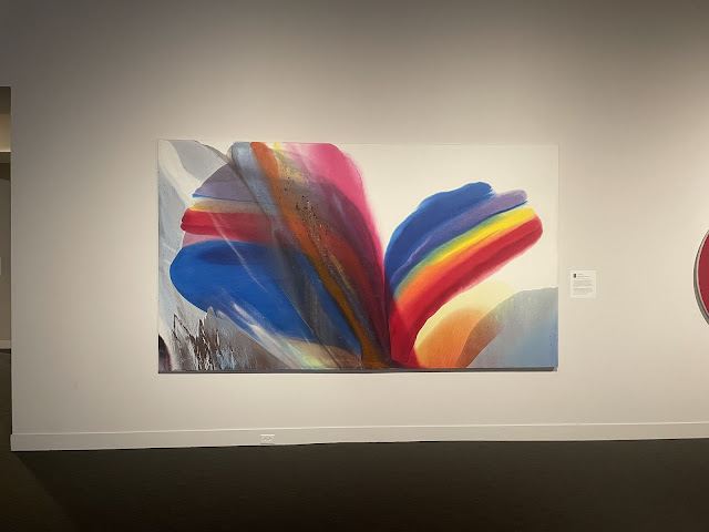 This painting is hard to describe. It is an abstract painting that is made to look like simplified butterfly wings viewed from the side of a butterfly. The wings are made up of most of the colors of the rainbow.