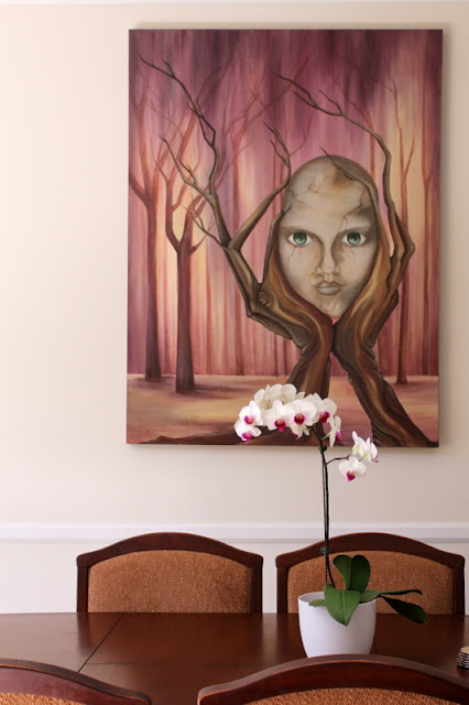 White moth orchid on a table with a painted art piece on the wall