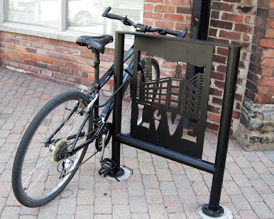 A bike rack featuring a cut out graphic of an industrial building and the word LIVE
