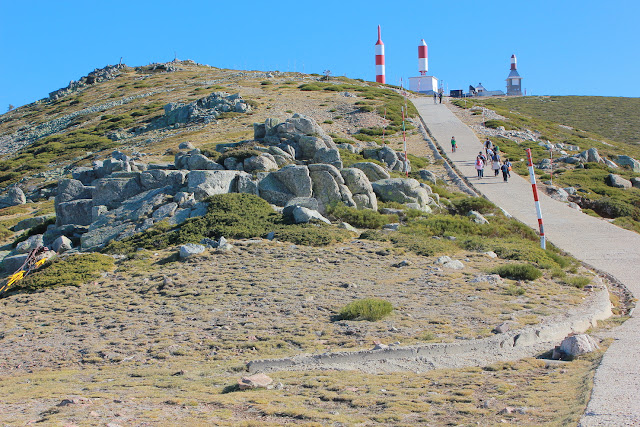 Spacer z przełęczy Navacerrada na szczyt Bola del Mundo należy do popularnych wycieczek w górach Guadarrama. Na szczyt, na którym stoi stacja przekaźnikowa, prowadzi wąska, asfaltowa drogą. Drogą idą pod góry grupy spacerowiczów.
