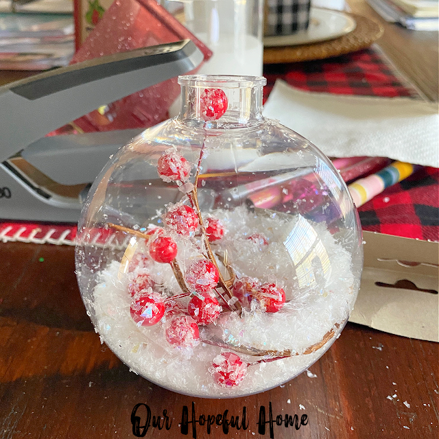 clear globe Christmas ornament filled with red berries and faux snow