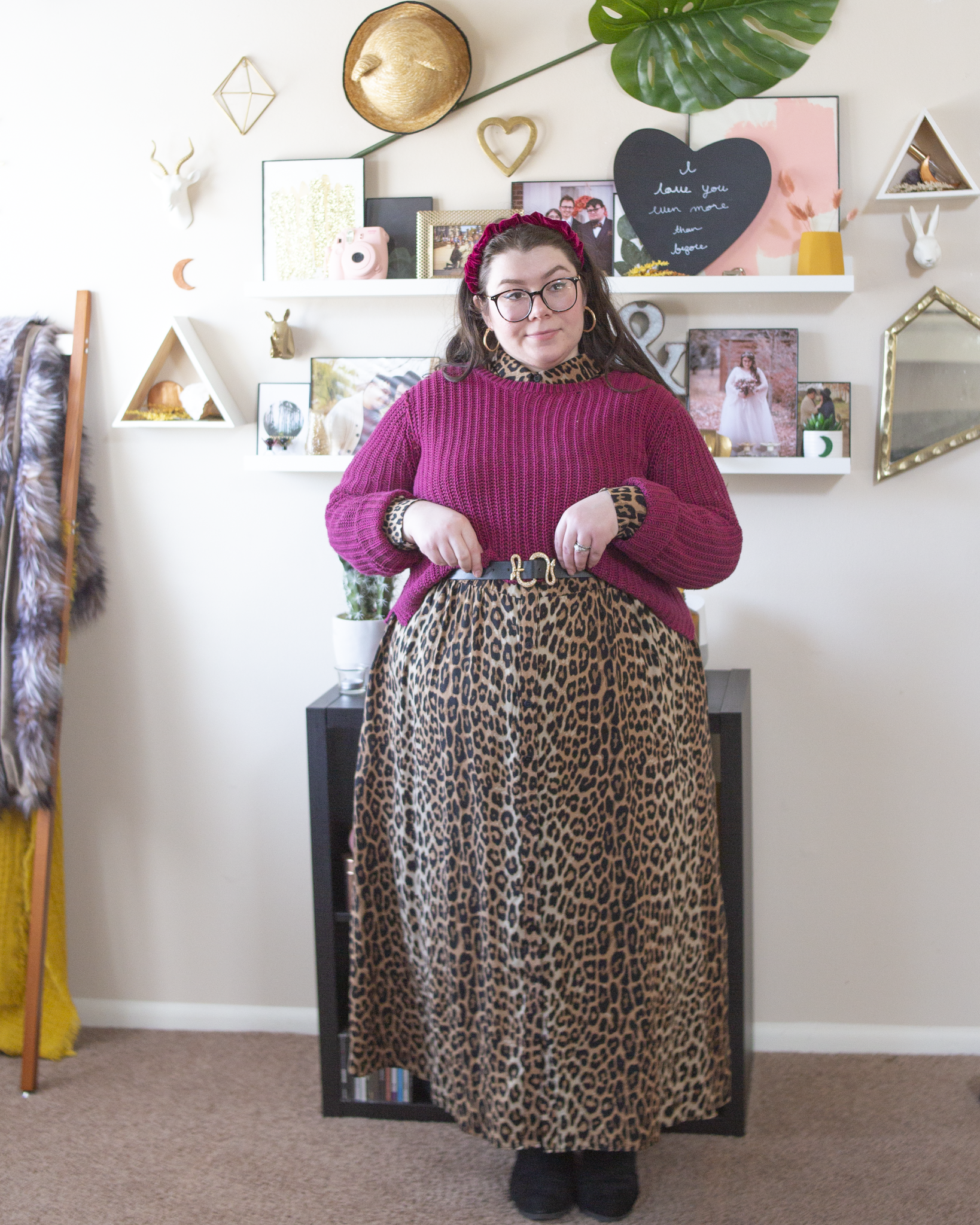 An outfit consisting of a maroon berry velvet headband, a maroon berry sweater over a brown leopard button down midi shirt dress and brown chelsea boots.