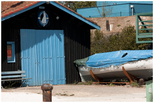 Cabaña negra con puerta azul y barca con lona azul