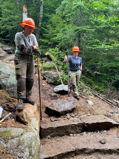 two female trail crew members build steps by hand on the Old Bridle path