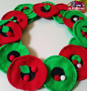 Image description: A festive wreath made out of red and green felt and decorated with small felt ornaments.