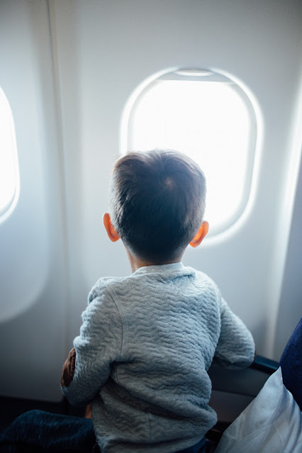 child looking out of airplane window:Photo by Hanson Lu on Unsplash