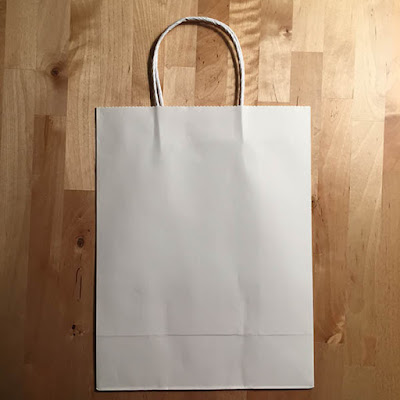 White paper craft bag on light wood table