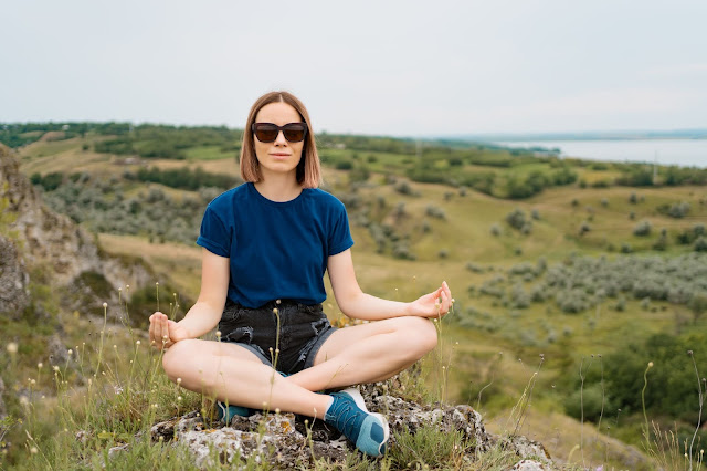 Meditation Benefits - Yoga woman meditating on hill peak cliff edge