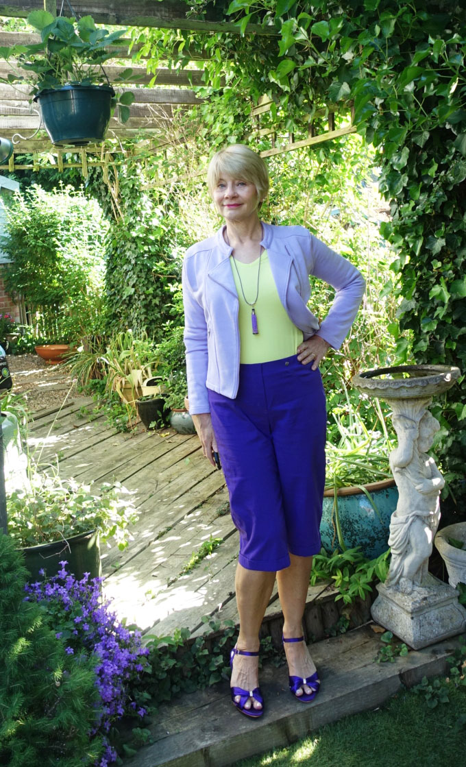 Gail Hanlon in smart casual wear: purple knee length shorts, lavender Chloe jacket by Kettlewell and acid yellow top