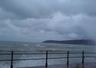 Grey rain clouds, heavy sea, headland and railing