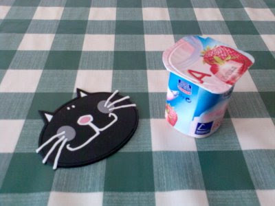 imagen de un yogurt al lado del posavasos de gato