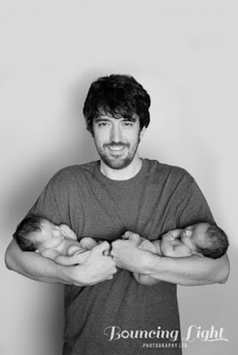 Dad holding twin newborn girls. 