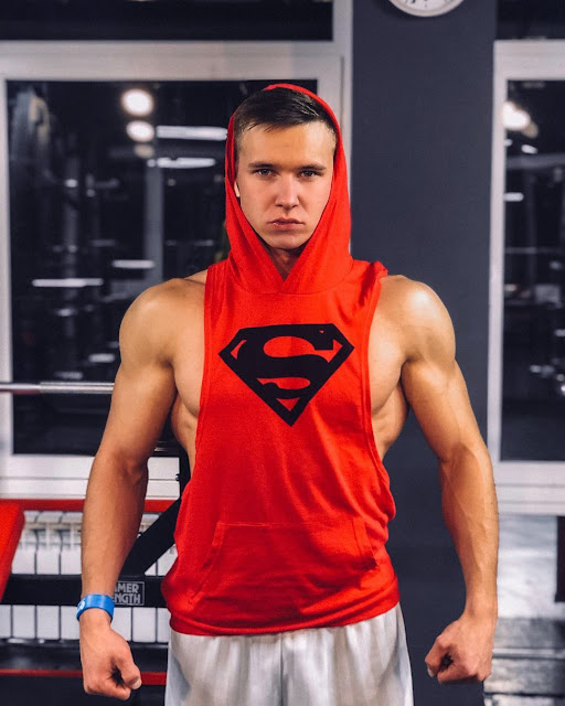 Aleksey Teterin wearing a sleeveless, deep-cup Superman hoodie in the gym