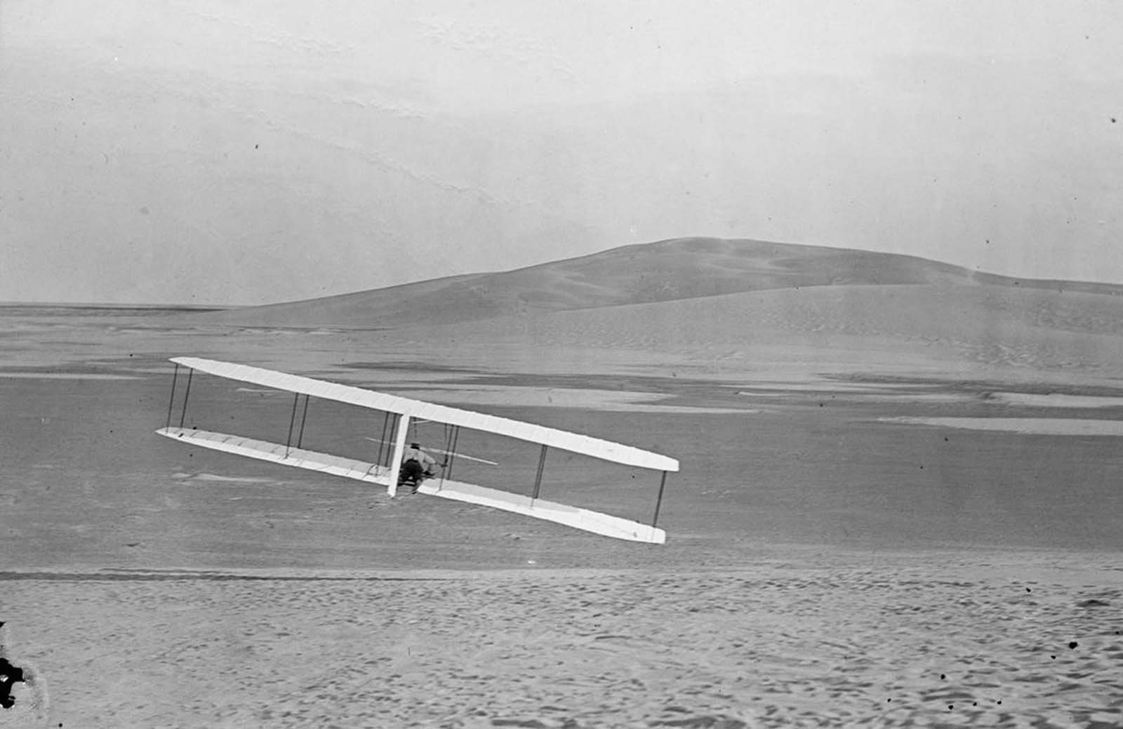 Rear view of Wilbur making a right turn in glide from No. 2 Hill, right wing tipped close to the ground, October 24, 1902.