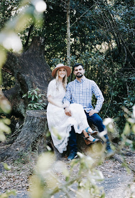 couple sitting on tree stump smiling