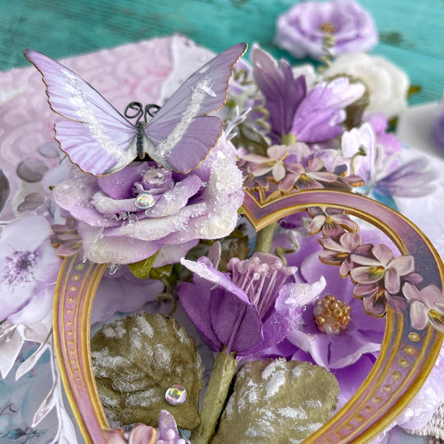 Purple Haze mixed media canvas created with: Prima aquarelle dreams paper, flowers, ephemera, acetate, lace, Reneabouquets butterflies, printed chipboard heart; Tim Holtz distress oxide milled lavender; Pinkfresh clear drops iridescent