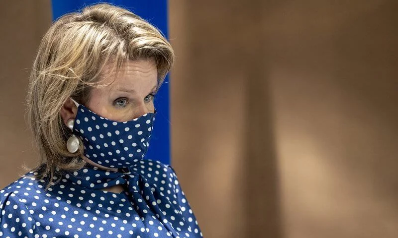 Queen Mathilde wore a navy polka-dot print tie neck blouse from Natan, and polka dot mask, white trousers