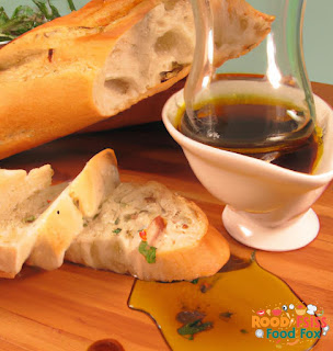  A photo of a sliced ciabatta bread with olive oil, balsamic vinegar, and herbs for dipping. 