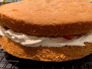 Two sponge cakes sandwiched with whipped cream and jam