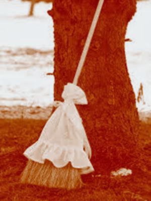 En la imagen un antigua escoba apoyada en un arbol