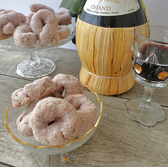 sugar coated red wine cookies on a glass pedestal and in a footed gold etched dish