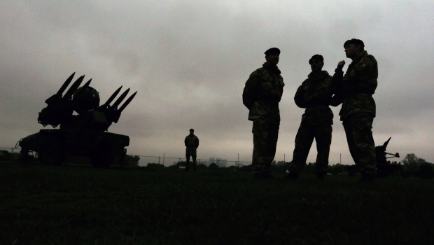 Members of the British military's Royal Artillery regiment are silhouetted as they stand near a Rapier air defence system 