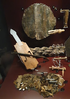 Museum display case showing items recovered from the wreck of 'The Mary Rose' including a fiddle, a home-made gaming board and a bundle of needles and thread