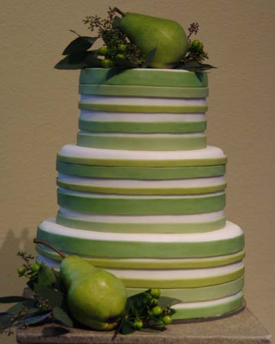 A tall two tier wedding cake in green with grass decorations