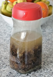 Sultanas soaking in water in a jar with a red lid.