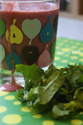 Kale berry smoothie dripping down the glass with fresh kale