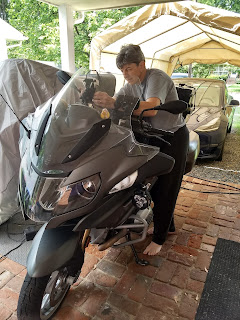 a dark grey motorcycle with a woman standing