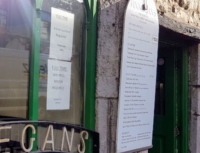staff wanted sign in the window of a traditional Irish restaurant called Finnegans - in a stone building with arched windows
