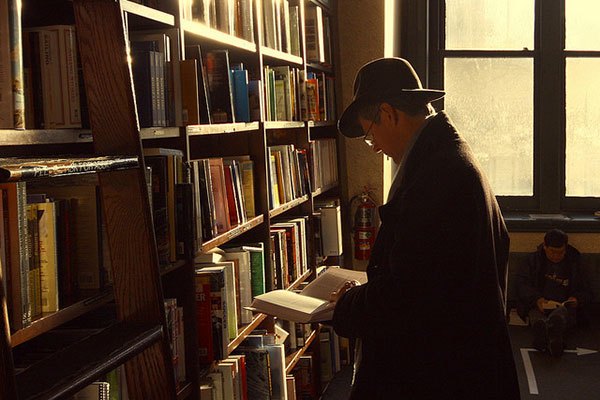 Un señor hojea un libro en una librería.