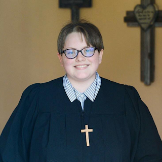 a younger, light-skinned woman with dark hair, wearing a pastoral robe