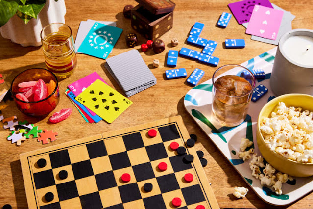 Aneka board game klasik, monopoli, domino, uno, catur, dan lainnya bertebaran di atas meja