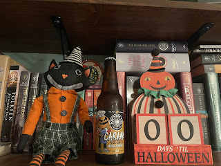 A bottle of Caramel Pumking between a Halloween cat decoration and a Halloween countdown decoration that displays 00 days until Halloween.