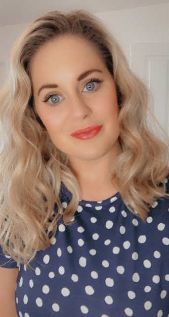 Lady taking a selfie, wearing a navy and white polkadot dress, with red lipstick on