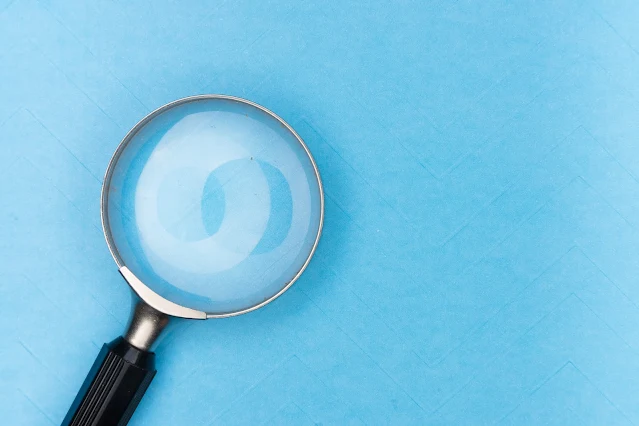 A magnifying glass emerges from the corner of a blue background.