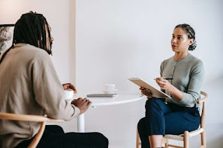 A man in dreadlocks talking to a woman, apparently in an interview.