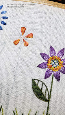Third flower motif being embroidered in oranges